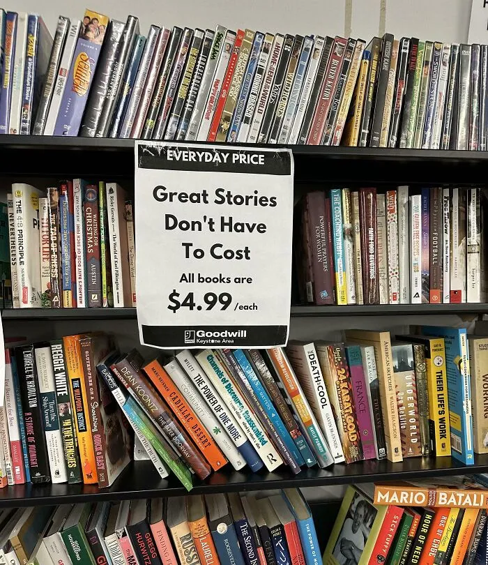 Books priced at $4.99 each on a thrift store shelf with DVDs overhead, showcasing ridiculous thrift store finds.