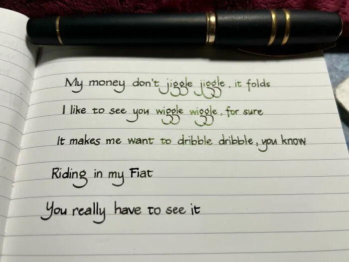 Handwriting example featuring neat, creative cursive and print styles written with a black and gold pen on lined paper.