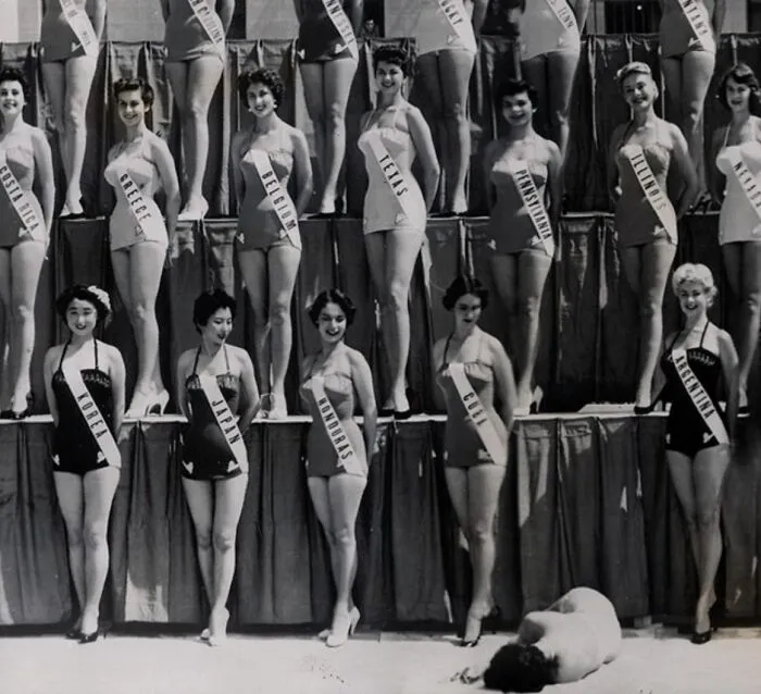 Mujeres con fajas representando países en concurso de belleza, foto inquietante en blanco y negro del pasado.