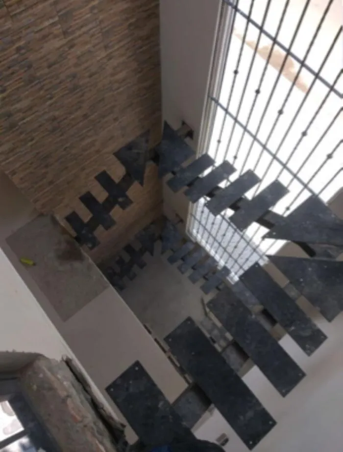 Looking Down A Window Lit Rail-Less Stairwell. Dark Planks Across A Central Point With No Added Support