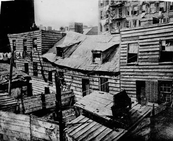 Old wooden houses and fences in a crowded urban area captured in a fascinating historical photo from the past.