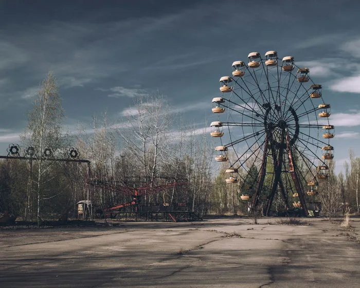 Abandoned Ferris wheel and deserted amusement park representing one of the scariest places around the world for brave travelers.