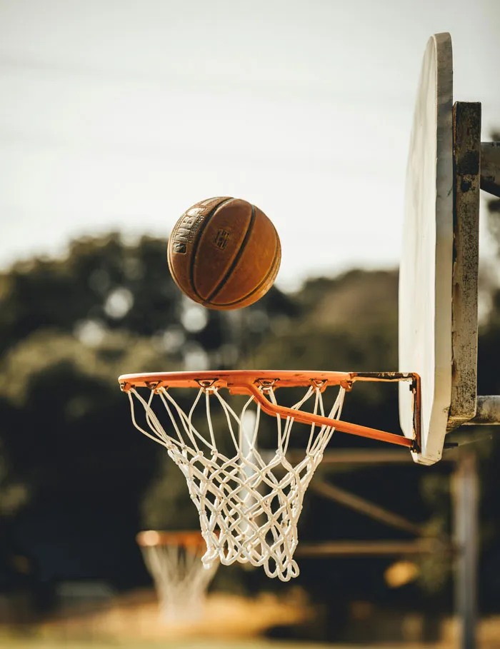 Basketball flying toward hoop outdoors, illustrating moments that reflect the biggest mistakes of their lives.