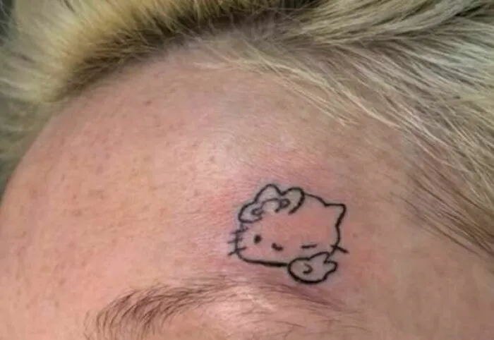 Small, poorly executed Hello Kitty tattoo on a person's forehead, an example of hilariously bad tattoos inkshaming.
