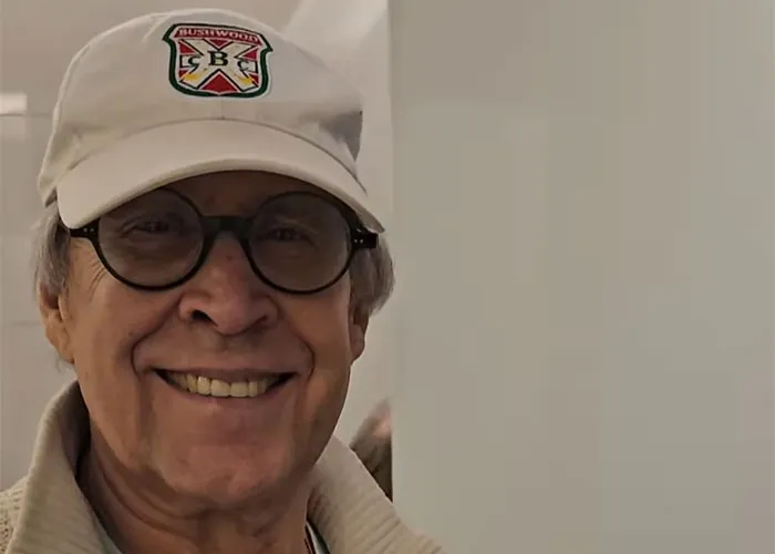 Smiling elderly man wearing glasses and a hat, sharing unbelievable experiences he can prove to skeptics.