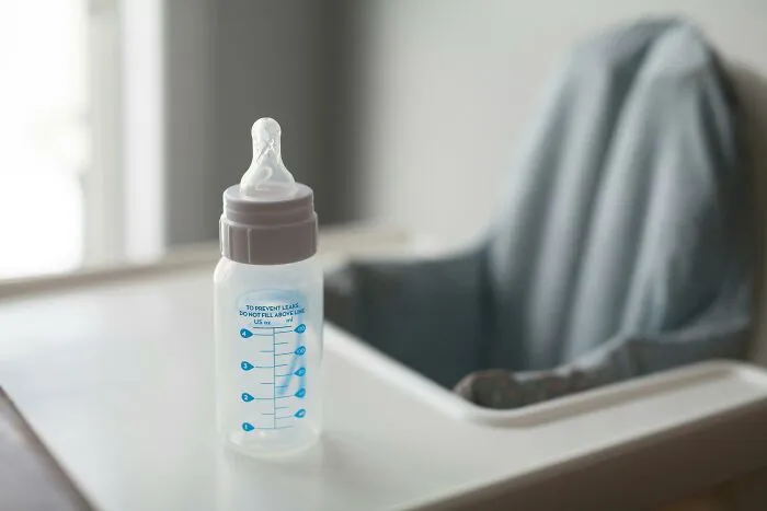 Baby bottle on a high chair with a cloth draped over the back, symbolizing disrespectful partner family stories.