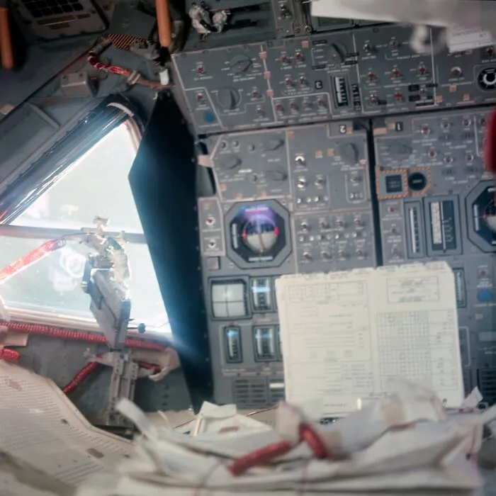 Apollo mission cockpit showing detailed control panels and documents inside the spacecraft during spaceflight.