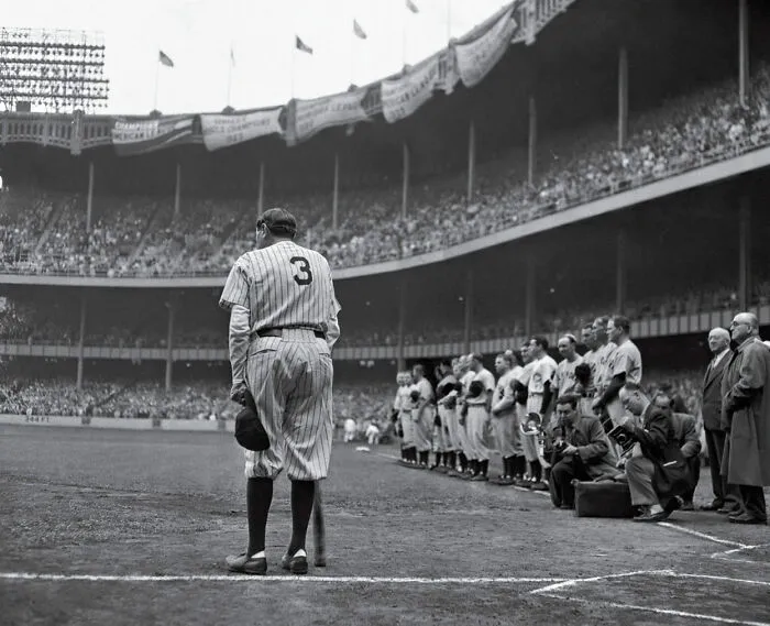 Last known photo of a famous baseball player standing on the field during a historic game with spectators in the background.