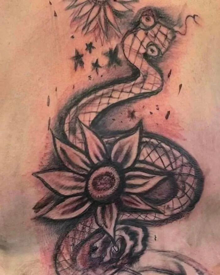 Abstract snake and flower tattoo with unusual design elements in black ink on skin, showcasing bizarre tattoo choices.