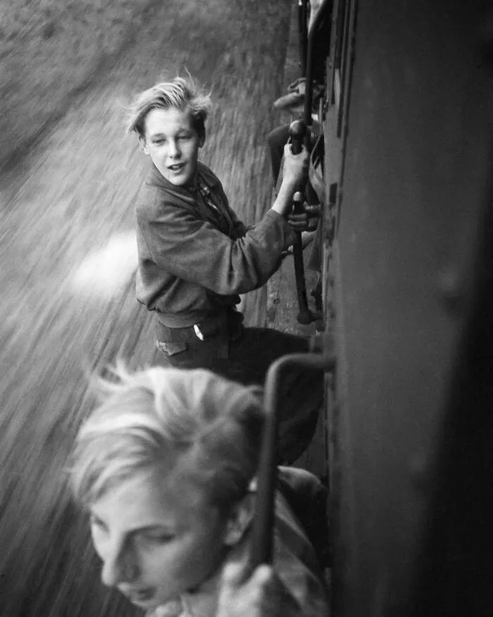 Two boys hanging off the side of a moving train, illustrating a historic moment to learn weird things about history.
