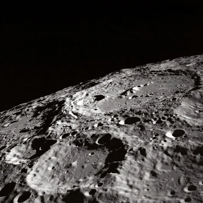 Apollo mission photo showing detailed lunar surface with craters under dark space background.