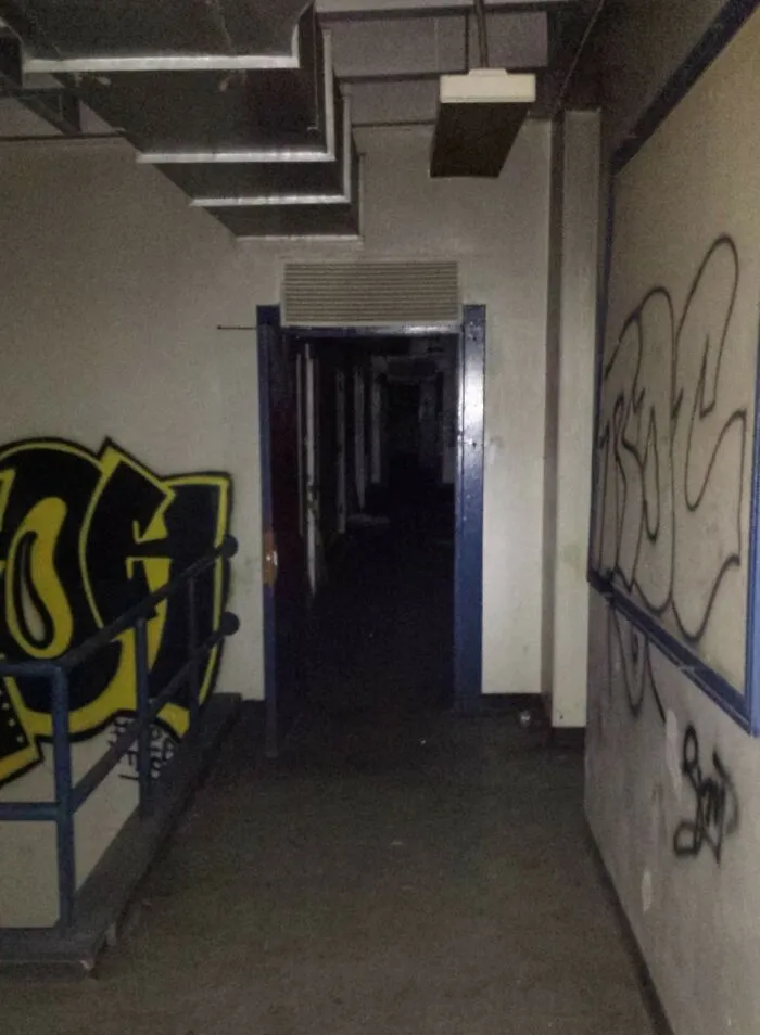 Dark abandoned hallway with graffiti on walls, showing eerie atmosphere experienced by explorers during creepy escapades.