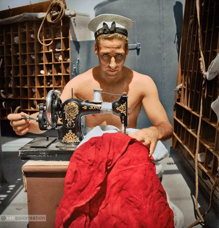 A British Sailor On Board Of The Hms Alcantara Uses A Portable Sewing Machine To Repair A Signal Flag During A Voyage To Sierra Leone Photographed By Cecil Beaton In March 1942