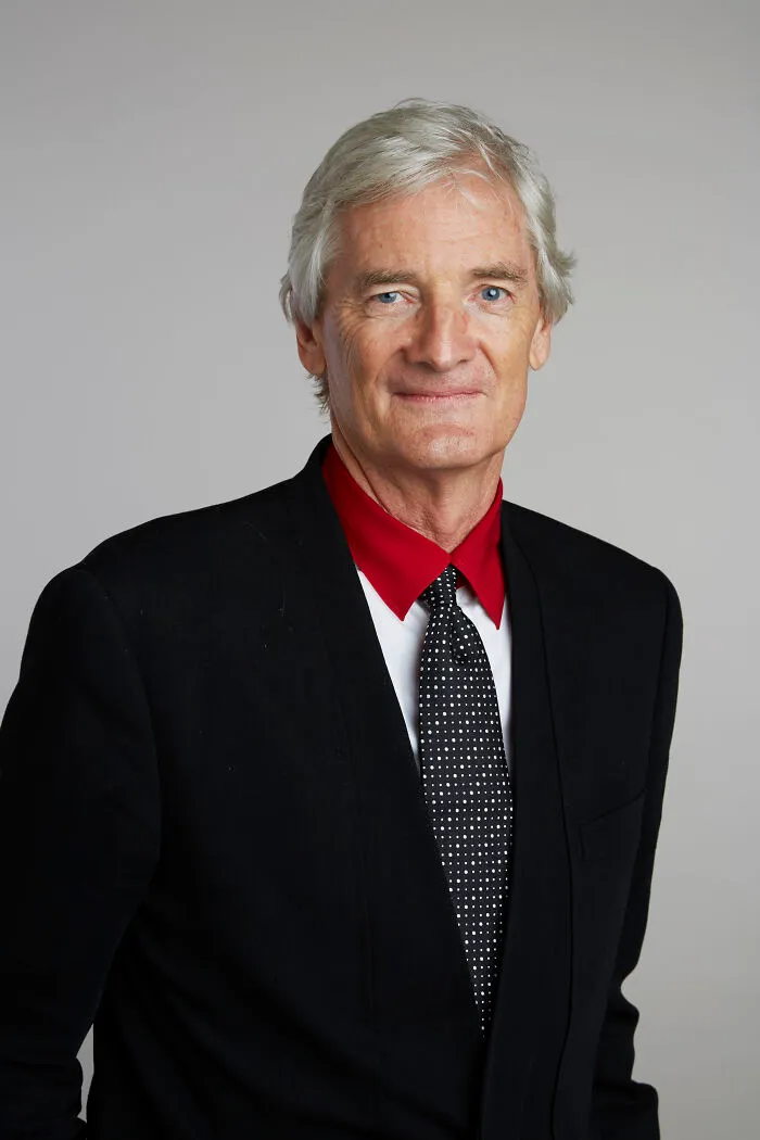 Older man with gray hair dressed in a black suit and patterned tie, representing late bloomers who became millionaires.