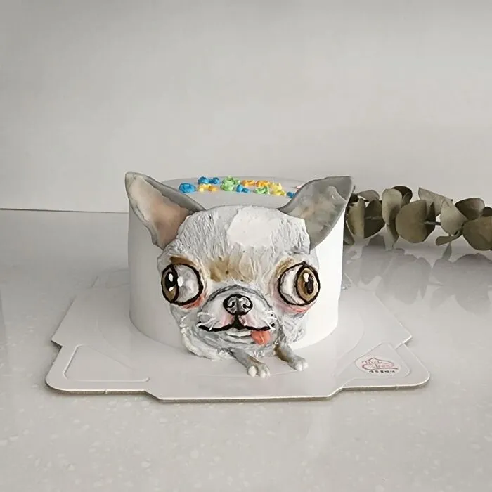 Pet-themed cake shaped like a white dog with large eyes and realistic texture capturing unique personality details.