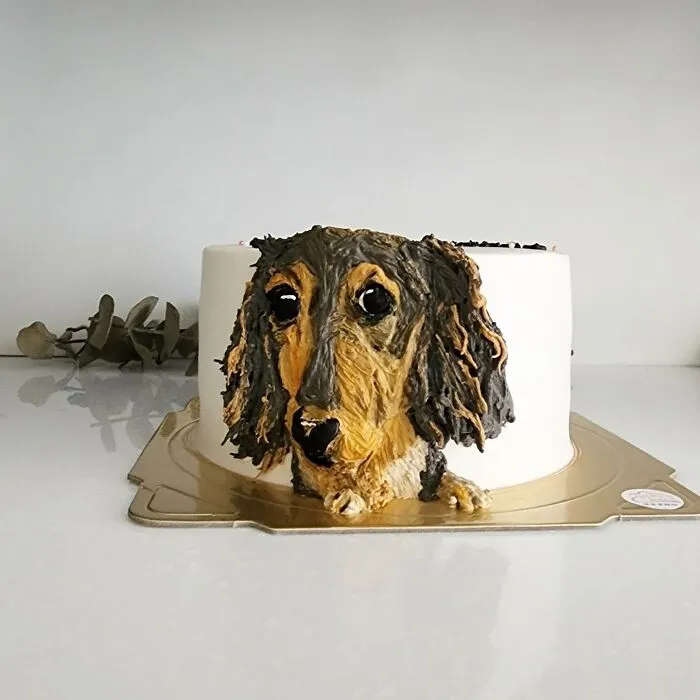 Cake with realistic pet-themed dog face design by artist capturing unique personality of the pet on a white background