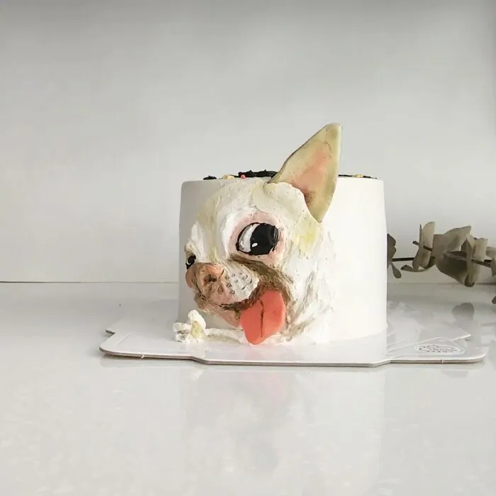 Pet-themed cake featuring a detailed dog face with tongue out, showcasing the artist's skill in capturing unique pet personality.