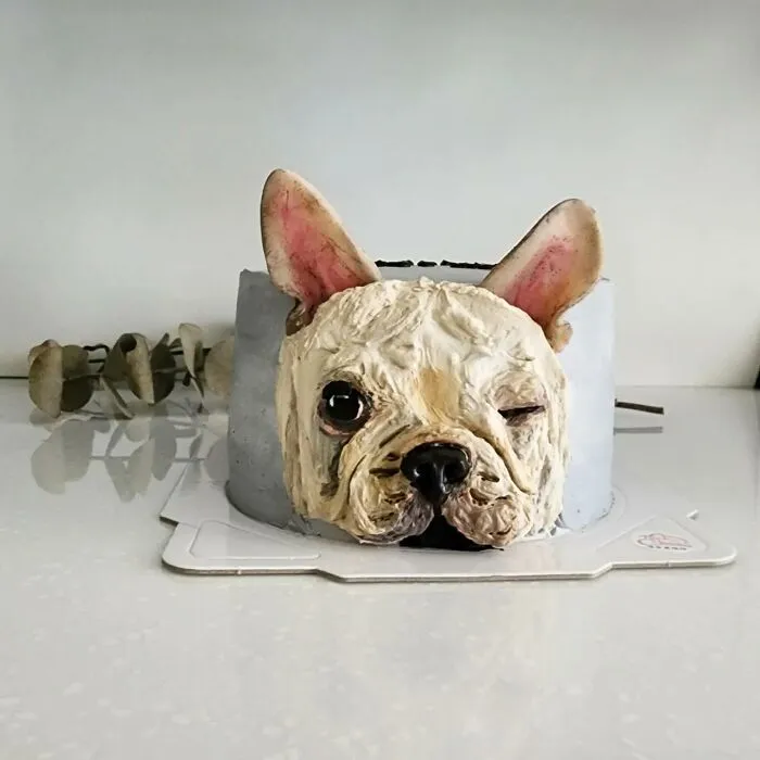 Pet-themed cake shaped like a winking French bulldog, showcasing the artist's skill in capturing unique pet personalities.