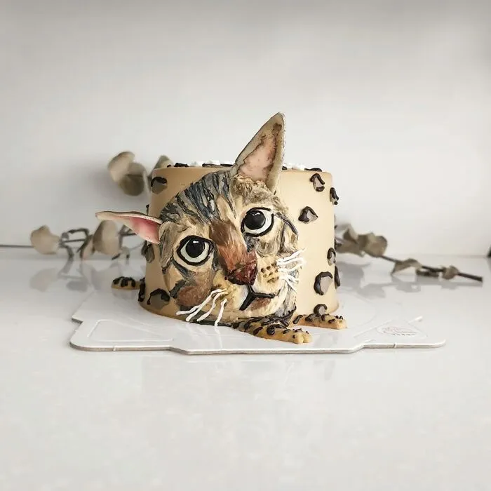 Pet-themed cake featuring a realistic cat face with detailed fur and expressive eyes, showcasing adorable edible art.