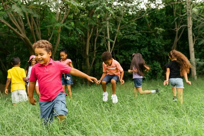 Children playing outdoors in a grassy field, enjoying unique childhood joys before the rise of smartphones.