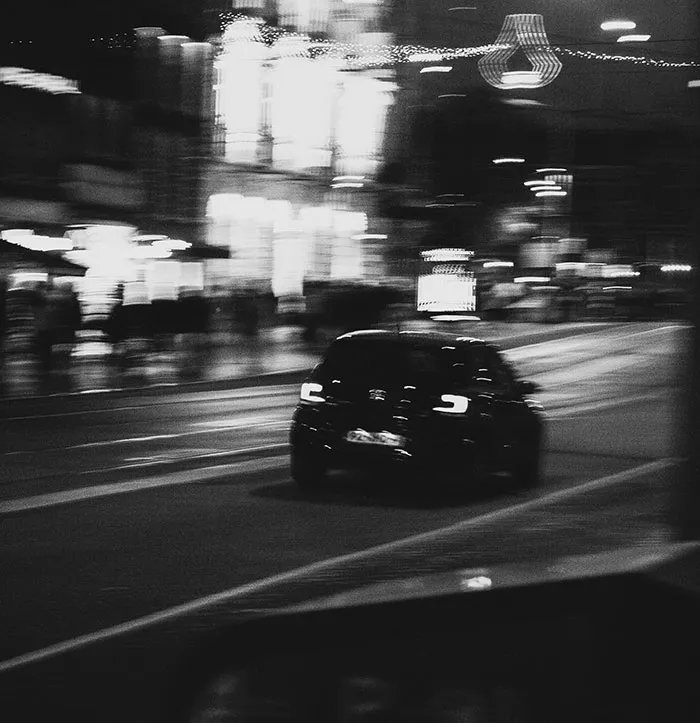 Blurry black car driving at night on a city street illustrating imperfections related to the human body flaws.