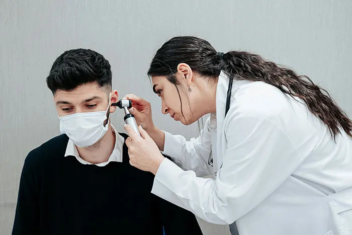 Doctor examining patient's ear with an otoscope highlighting common flaws of the human body during a medical checkup.