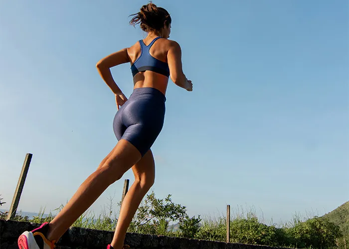 Woman running outdoors on a trail, wearing athletic wear, representing habits that may improve your quality of life.