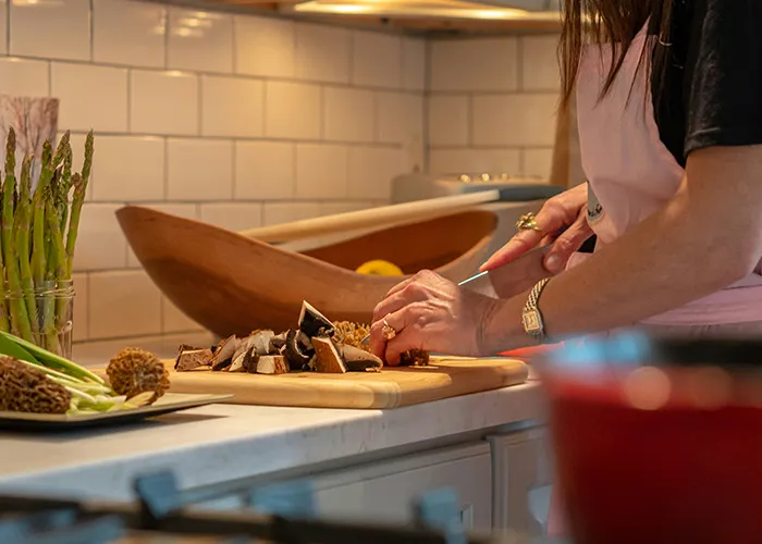 Person chopping mushrooms on a cutting board in kitchen, demonstrating habits that may improve your quality of life.