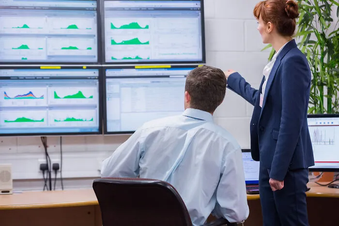 Two corporate colleagues reviewing data on multiple screens, illustrating ways to call out corporate pals’ lies.
