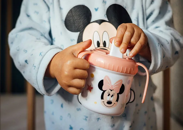 Toddler in pajamas holding a Minnie Mouse sippy cup, illustrating funny and inappropriate things kids have blurted out.