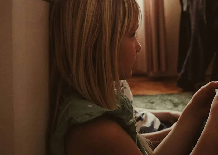 Young child sitting indoors, sharing some of the funniest and most inappropriate things kids have blurted out moments.