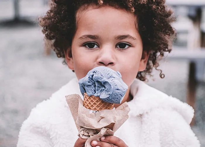 Child enjoying a blue ice cream cone outdoors, capturing funny and inappropriate things kids have blurted out moments.