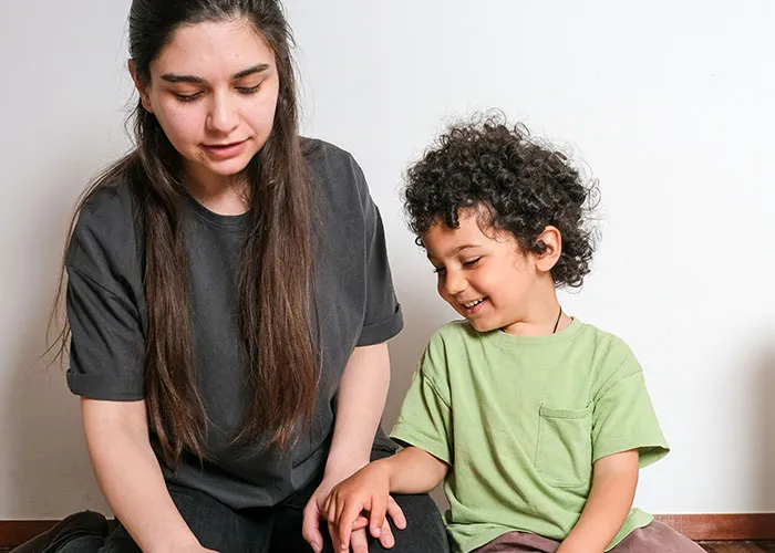 Woman and child sitting on floor smiling and interacting, capturing funny and inappropriate things kids have blurted out.
