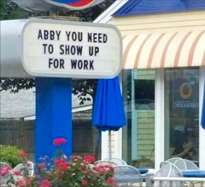 Outdoor sign humorously reminding Abby to show up for work, adding to hilarious signs that create chaos in the world.