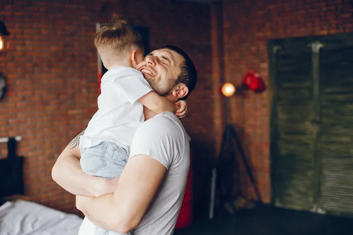 Man joyfully hugging child indoors, capturing a warm moment perfect for history people would love to call theme.