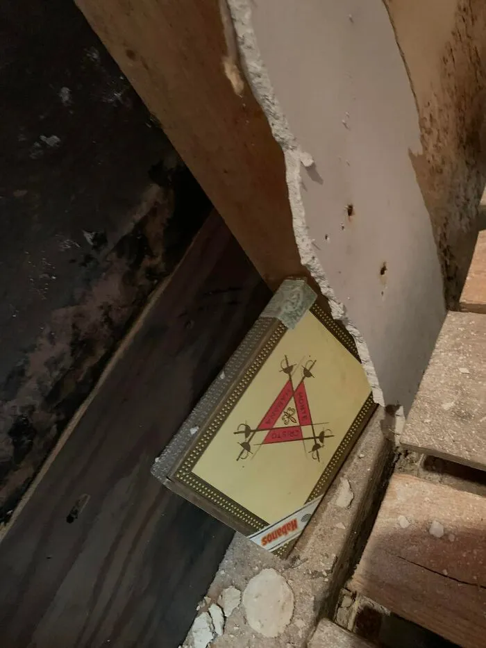 Old cigar box found hidden behind a wall panel in a home, one of the unexpected things found in walls and hidden places.