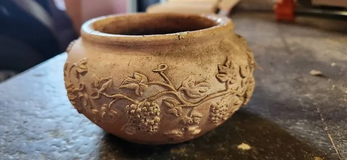 Clay pot with grapevine carvings, one of the unexpected things found in walls and other hidden places in homes