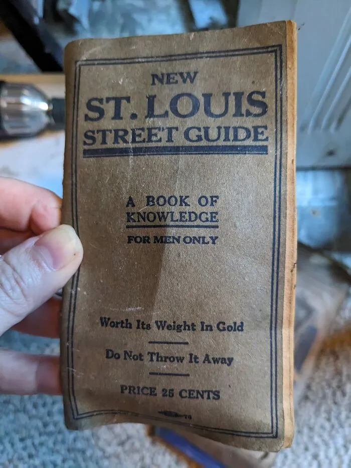 Hand holding an old St. Louis street guide found hidden in walls with unexpected things in homes.