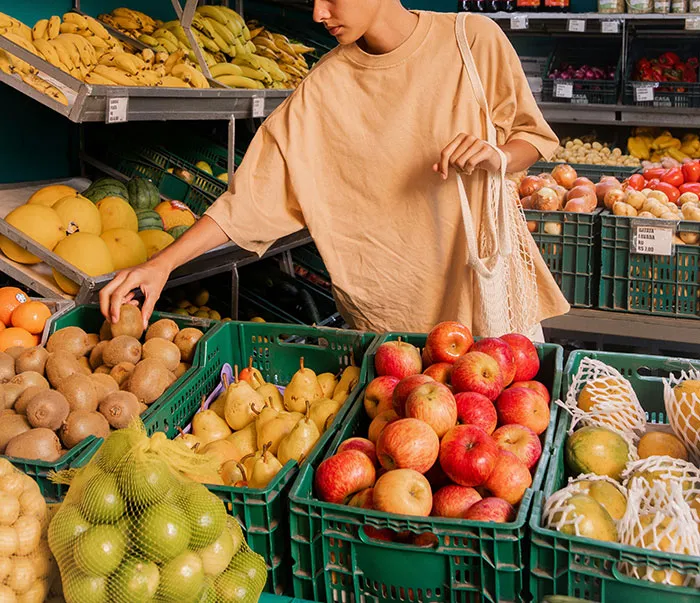 Person shopping for fresh fruits at a market, illustrating healthy habits to keep the brain active and healthy.