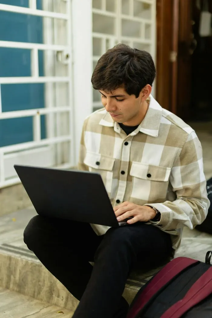 Young man using laptop outdoors, sharing best I Was There When It Was Written moments in a casual setting.