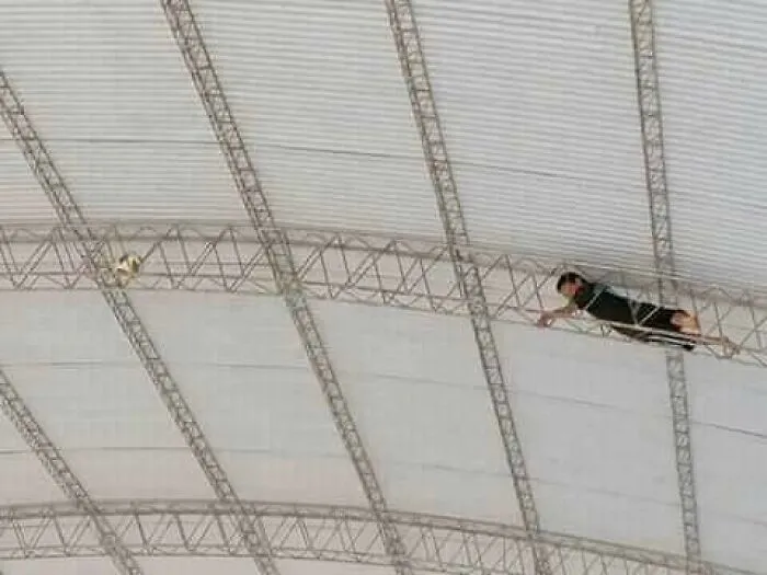 Hombre realizando acrobacia aérea en trapecio, reflejando esfuerzo y concentración, relacionado con razones de longevidad femenina.