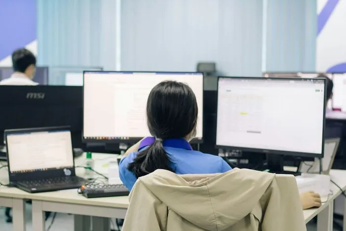 Person working at desk with multiple screens, representing people sharing things they thought everyone knew but don’t.