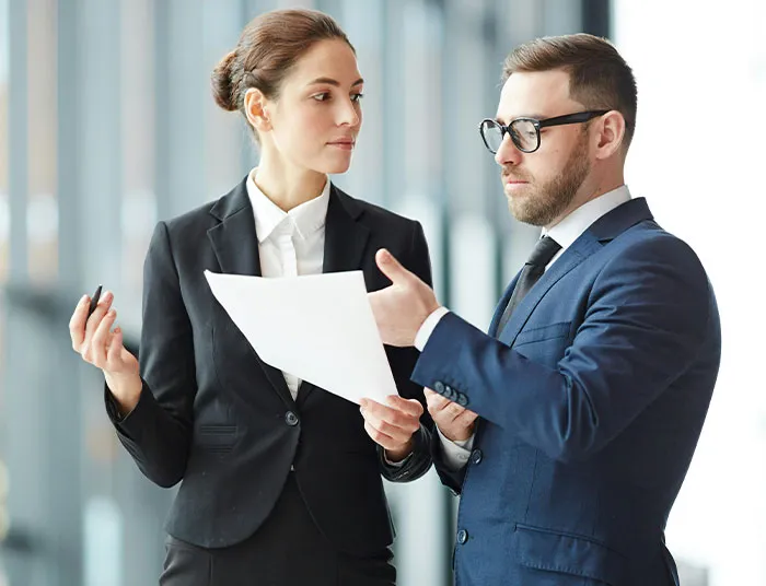 Two professionals in business attire discussing legal documents, representing absurd legal claims and lawyer consultation.