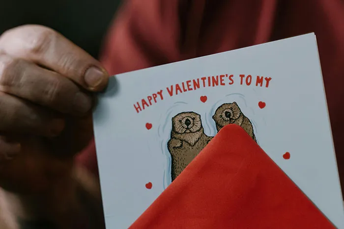 Close-up of hands holding a Valentine’s card with otter illustrations, symbolizing heartfelt moments for healthcare workers.