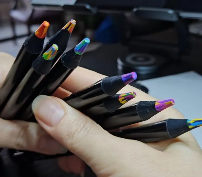 Hand holding multicolored artisan pencils showcasing trending products in the Pandaverse virtual marketplace.