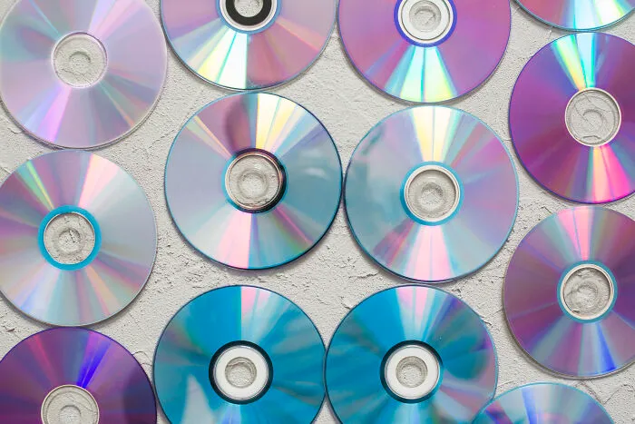 Multiple compact discs arranged on a textured surface representing outdated online skills from before the 2000s.