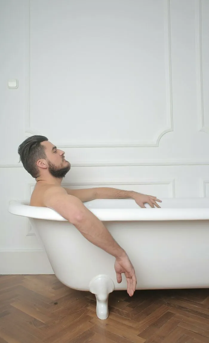 Man with beard relaxing in bathtub, capturing an insane hospital experience resembling a medical drama scene.