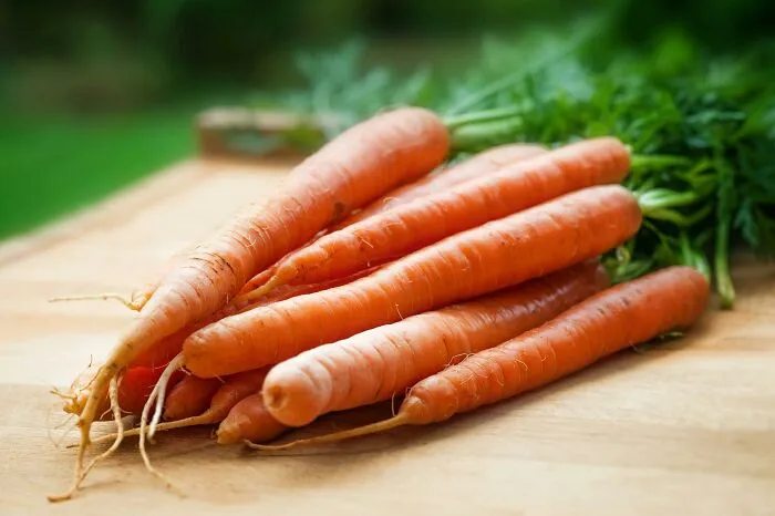 Fresh carrots on a wooden surface, illustrating fictional things people are still falling for despite never being real.