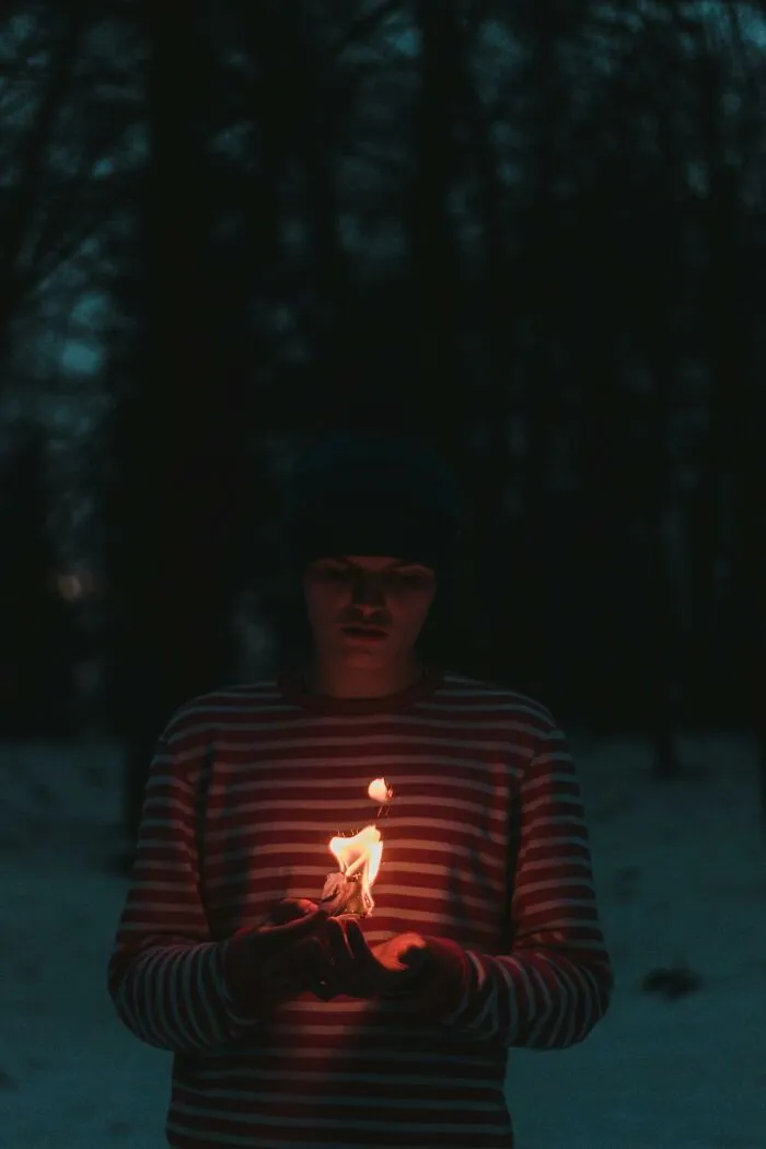 Person holding a small flame in dark outdoor setting evoking a dramatic and intense hospital experience vibe.