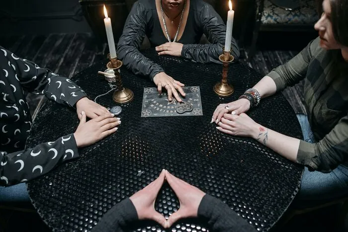 People gathered around a Ouija board with candles, illustrating fictional things people still believe are real.